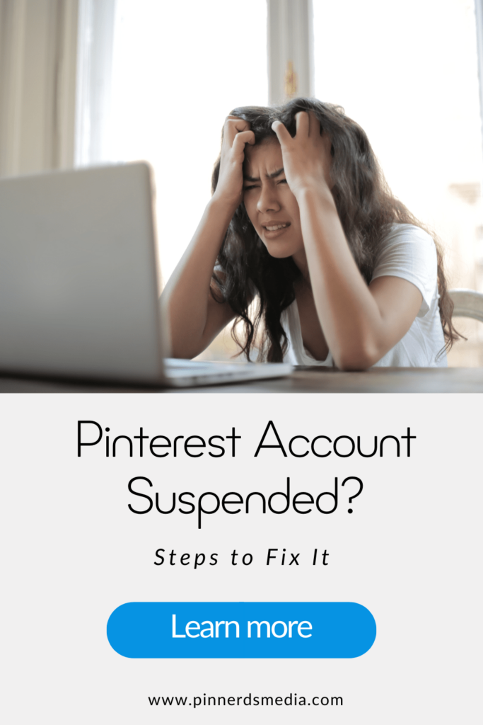 A frustrated woman sitting in front of her laptop, holding her head in her hands, representing Pinterest account suspension concerns.